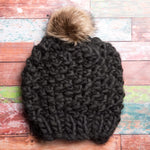 A generous faux fur pom-pom looks like real fur, on a colorful chunky knit hat.