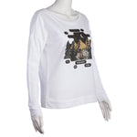 White long-sleeved pullover. Graphic includes mountains, evergreen trees, moon and stars, and a bear with flowers in her hair.