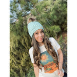 A generous faux fur pom-pom looks like real fur, on a colorful chunky knit hat.